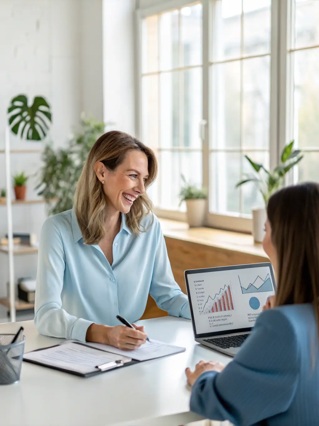 A female business coach in a one-on-one session with a woman entrepreneur, reviewing financial documents and discussing investment strategies in a bright, collaborative workspace.